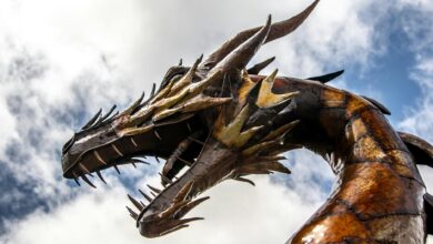 A striking low-angle view of a dragon statue set against a cloudy sky.