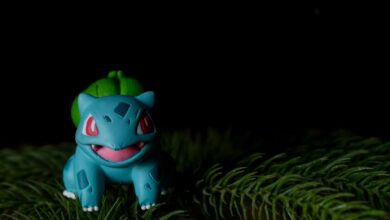 Vibrant Bulbasaur toy placed on pine needles with a dark background.