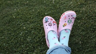 Feet in pink Crocs with playful sock designs resting on grass, depicting leisurely outdoor relaxation.