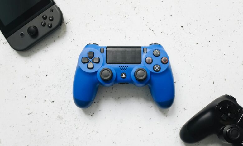 A top view of various colorful gaming controllers on a white surface.