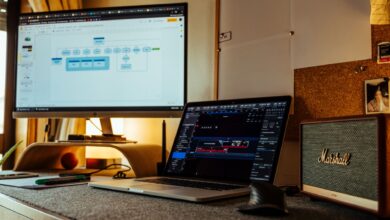 Cozy home office with laptop, large monitor, and speakers, ideal for productivity and digital work.