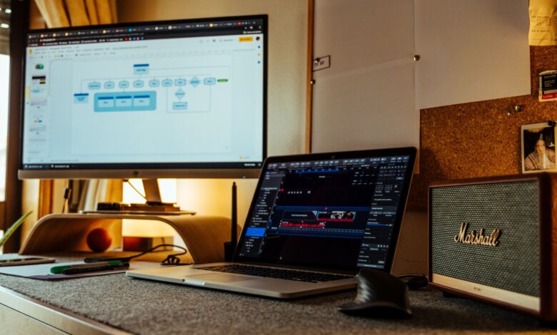 Cozy home office with laptop, large monitor, and speakers, ideal for productivity and digital work.