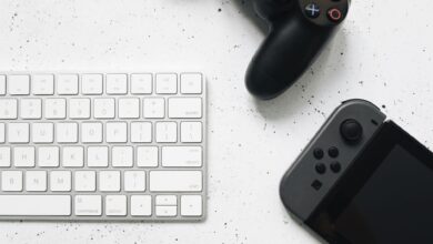 Close-up of a wireless keyboard and gaming controllers on a marble surface.