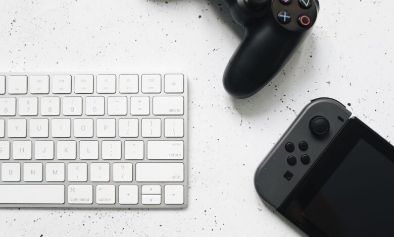 Close-up of a wireless keyboard and gaming controllers on a marble surface.