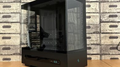 Sleek black and glass computer case with futuristic design on a wooden tabletop.