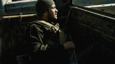 A soldier rests in an old vehicle, conveying determination and resilience in challenging environments.