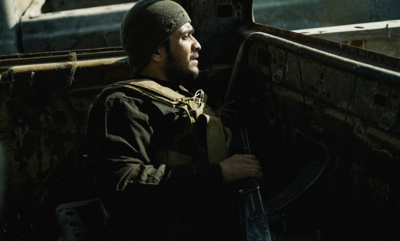 A soldier rests in an old vehicle, conveying determination and resilience in challenging environments.