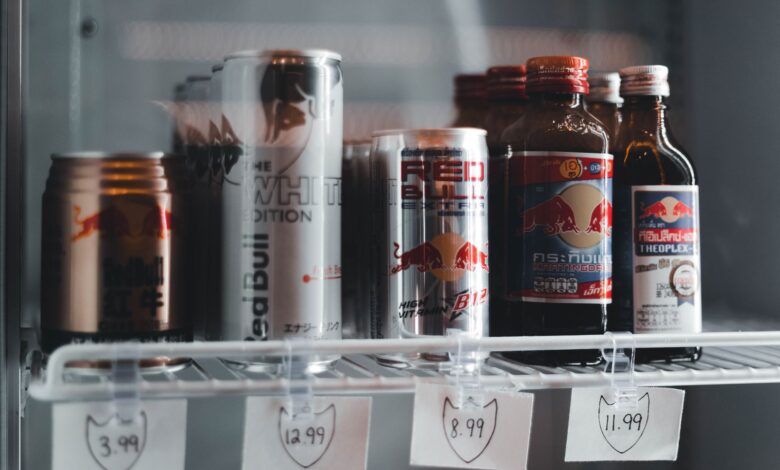 Variety of energy drinks displayed with prices on a refrigerator shelf.