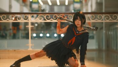 Cosplayer in dynamic pose with weapon in a modern indoor setting, showcasing intricate costume details.
