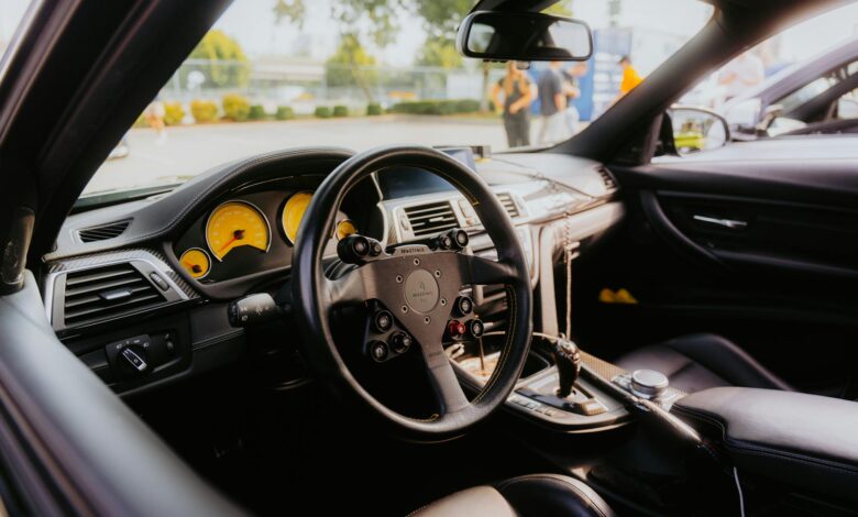Interior of a luxury sports car with yellow dashboard gauges and custom steering wheel.