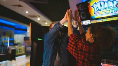 Energetic couple having fun at an arcade, sharing a high five and laughter.