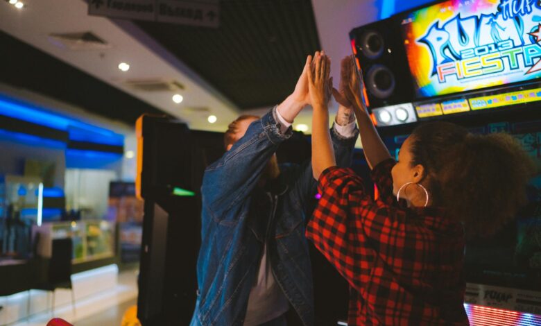 Energetic couple having fun at an arcade, sharing a high five and laughter.