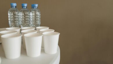 Close-up of disposable cups and bottled water with copyspace on a white table.