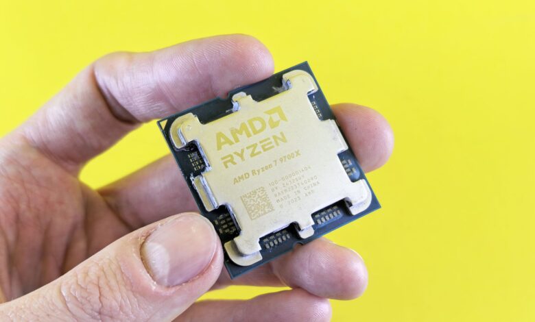 Detailed shot of AMD Ryzen 7 9700X processor held against bright yellow background.
