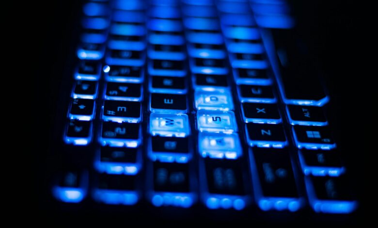 Close-up shot of a vibrant blue backlit keyboard keys on a laptop.