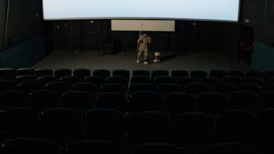 A custodian cleaning an empty cinema auditorium after a movie showing.