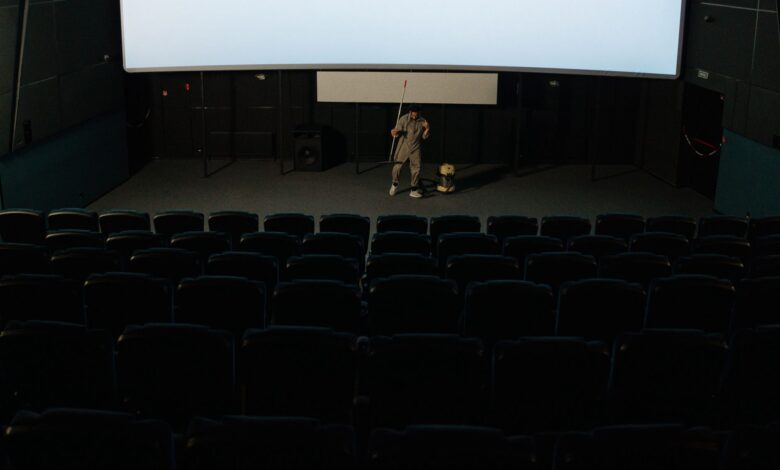 A custodian cleaning an empty cinema auditorium after a movie showing.