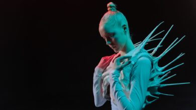 A woman in a spiky sci-fi costume on a black background, evoking an extraterrestrial theme.