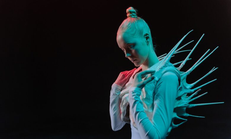 A woman in a spiky sci-fi costume on a black background, evoking an extraterrestrial theme.