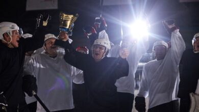 A joyful hockey team celebrates victory holding the trophy on the ice rink.