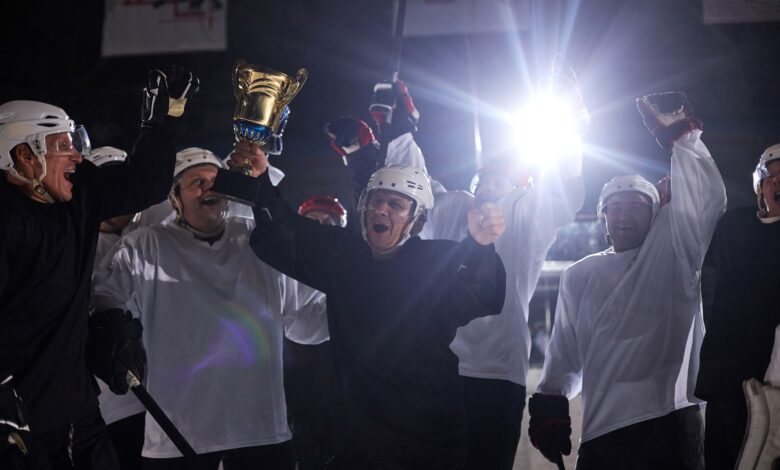 A joyful hockey team celebrates victory holding the trophy on the ice rink.