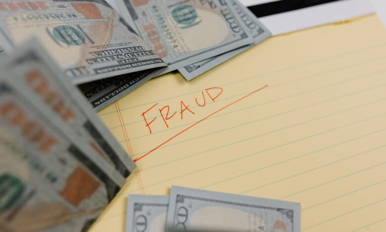 Close-up of US dollars and 'Fraud' written on yellow paper, representing financial scams.