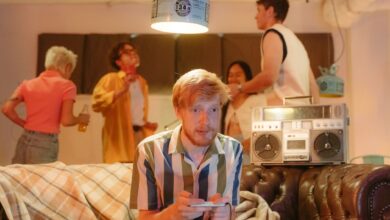 A group of young adults enjoying a retro-themed party with video games and a boombox.