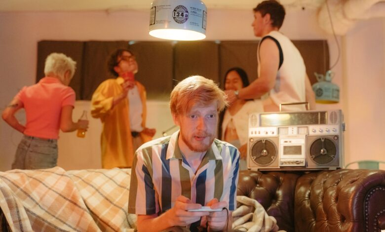 A group of young adults enjoying a retro-themed party with video games and a boombox.