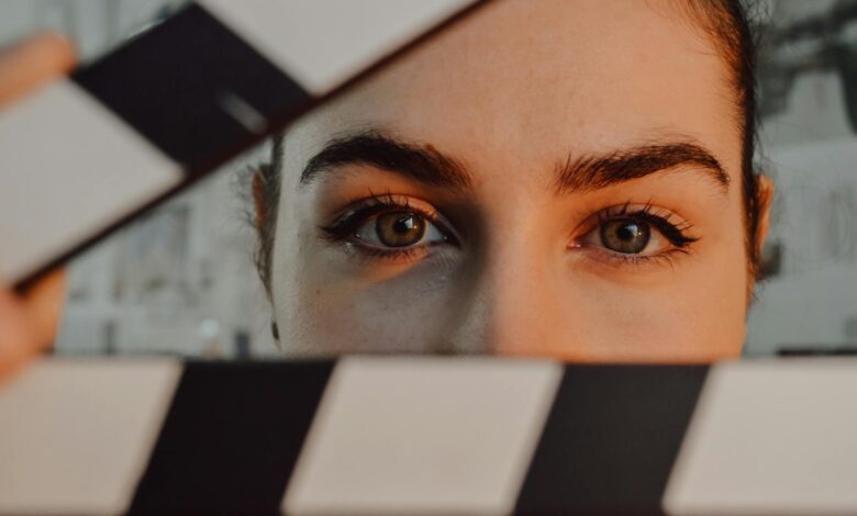 Intriguing close-up of a person's eyes behind a movie clapperboard, symbolizing filmmaking artistry.