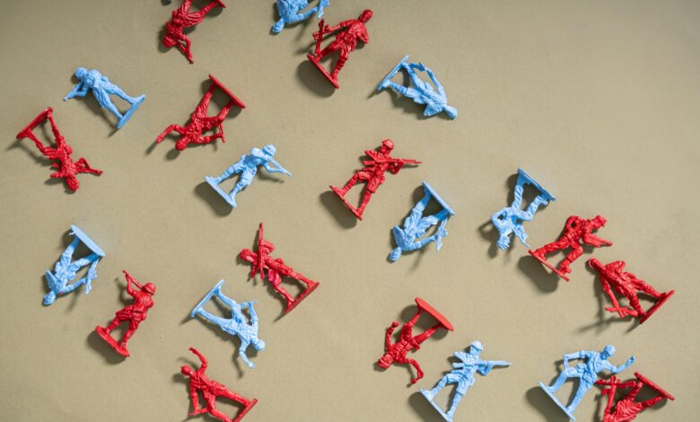 Red and blue toy soldiers arranged on a beige background, artistic flat lay.