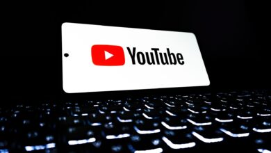 YouTube app icon displayed on a smartphone over an illuminated keyboard, representing digital media and online streaming.