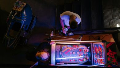 Overhead view of pinball game being set up in a retro arcade setting.