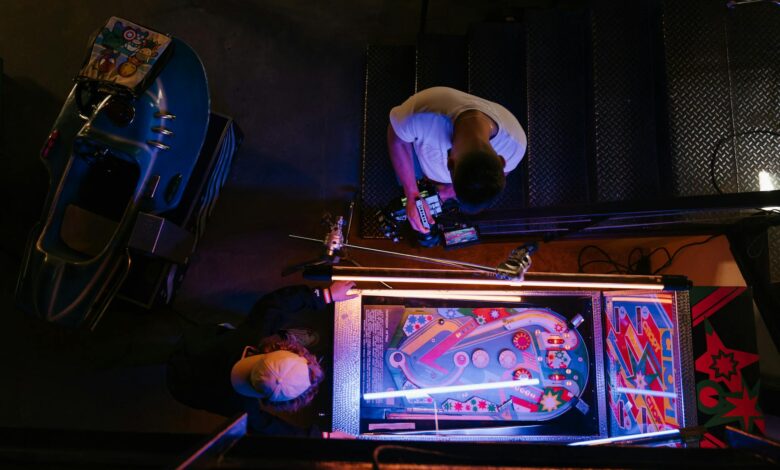 Overhead view of pinball game being set up in a retro arcade setting.