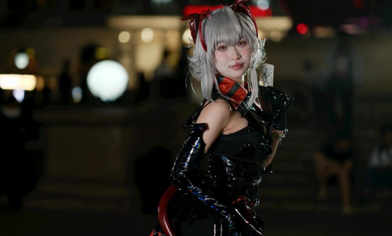 A cosplayer in a captivating futuristic costume poses outdoors during a night event.