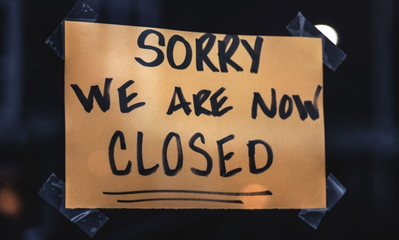 A handwritten sign with 'Sorry We Are Now Closed' in a dark window setting.