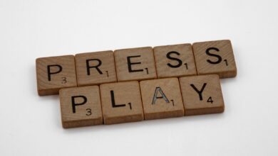 Scrabble tiles arranged to spell 'Press Play' on a white background.
