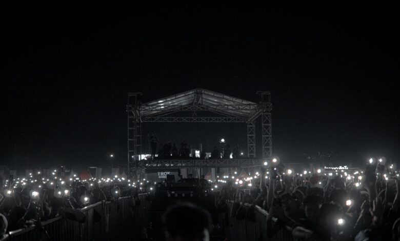 A captivating night concert with a crowd holding phone lights, creating a starry ambiance.