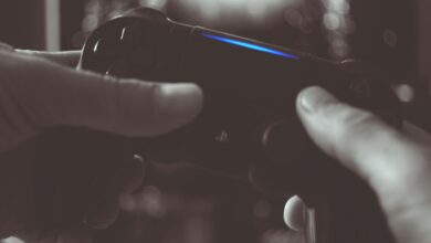 Close-up of hands gripping a gaming controller in dim light, emphasizing electronic entertainment.