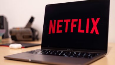 Close-up of a MacBook Pro showing Netflix on the screen in a modern workspace.