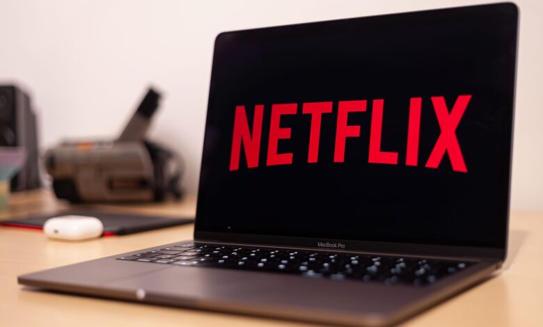 Close-up of a MacBook Pro showing Netflix on the screen in a modern workspace.