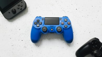 A top view of various colorful gaming controllers on a white surface.