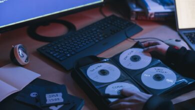A close-up of CDs and disks on a desk, featuring hands in a tech environment.