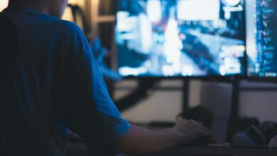 A man intensely focused on a computer screen in a dimly lit room, showcasing concentration in technology.