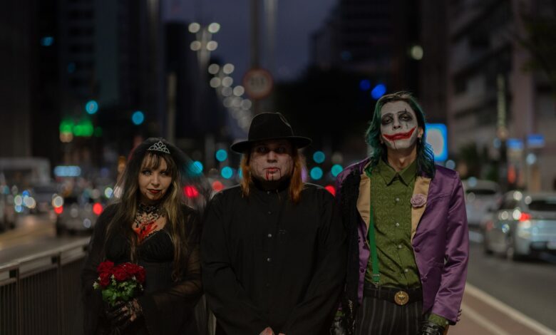 A trio in Halloween-themed cosplay walking through a bustling city street at night.