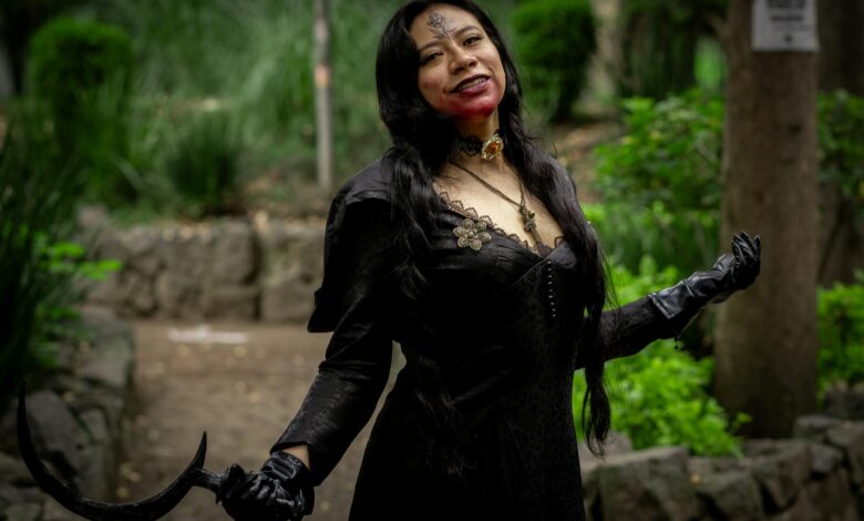 Woman in dark Halloween costume with fake blood in a garden setting, Mexico.