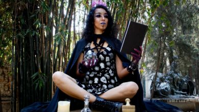 A mysterious woman conducts a witchcraft ritual with candles and potions in a forest.