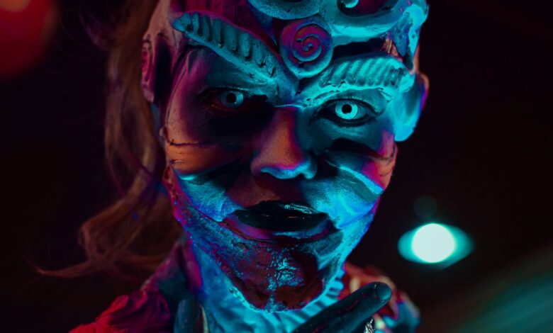 Close-up of a mysterious creature with creative prosthetic makeup under neon lights, perfect for Halloween themes.