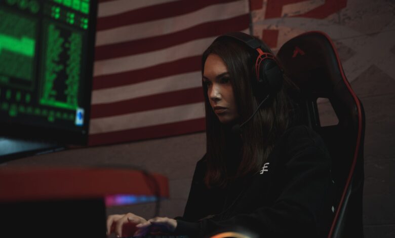 A female gamer intensely focused on her screen, wearing a headset in a dark room with neon green lighting.