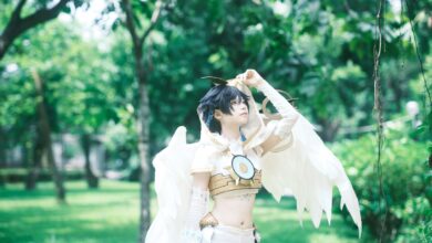 Cosplayer with wings in a vibrant green park environment.