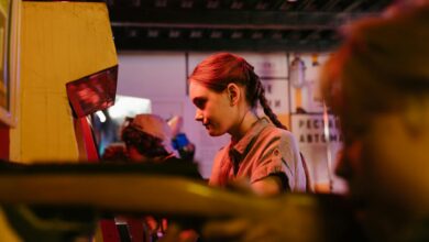 Teens playing at a vintage arcade with colorful lighting creating a nostalgic atmosphere.